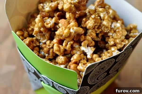 A decorative green container filled with golden, crunchy butter toffee popcorn with visible peanuts.