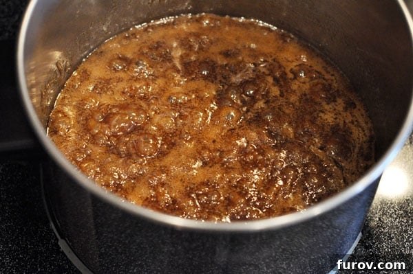 The sugar mixture vigorously boiling in a saucepan, a critical stage in caramel preparation.