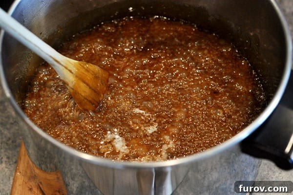 The boiling sugar toffee mixture in a saucepan, thick and golden brown, immediately after simmering.