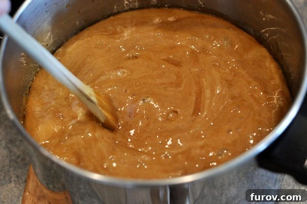 The golden brown toffee mixture in a saucepan after baking soda has been added, showing a slight foaming effect.