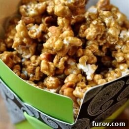 Close up of a generous serving of homemade butter toffee popcorn with peanuts.