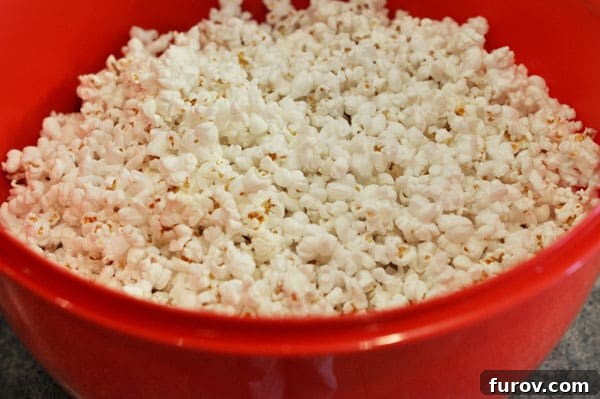 Fluffy, popped popcorn ready in a vibrant red bowl, awaiting the rich toffee coating.