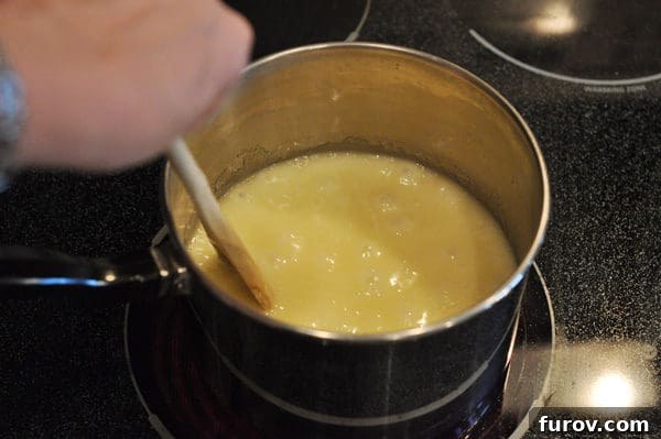 The butter and sugar mixture is actively bubbling in a saucepan, being stirred with a wooden spoon as it approaches the hard crack stage.