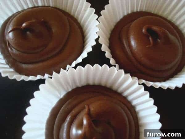 Peanut Butter Pods 2 Three decadent solid peanut butter cups resting in white muffin liners, ready to be enjoyed.
