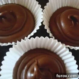 A top-down view of three creamy solid peanut butter cups, perfectly set in their white paper liners.