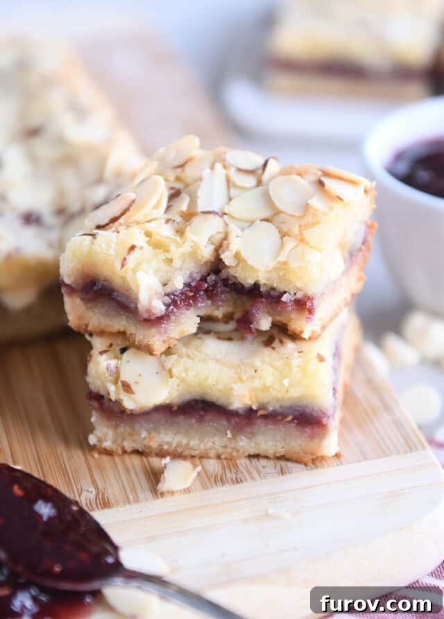 Luscious Raspberry White Chocolate Blondies 2 Two raspberry white chocolate blondie bars on wood cutting board with bite taken out of top bar.