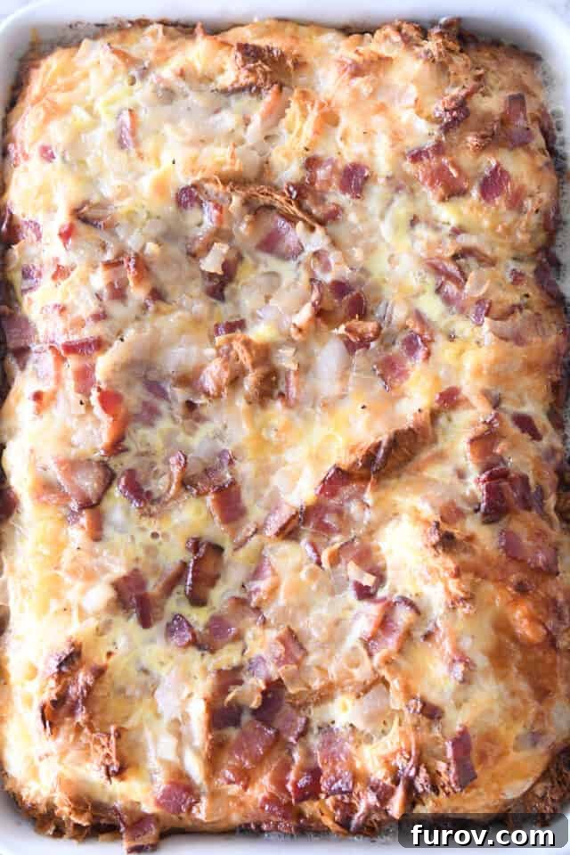 Overnight Croissant Bacon & Cheese Strata 6 The golden-brown, puffy, and perfectly baked croissant breakfast casserole filling a white 9X13-inch pan, ready to be served.