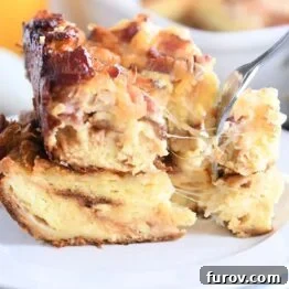 cheese strings pulling as fork takes bite from breakfast casserole on white plate
