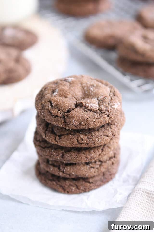 Stack of five perfectly baked chewy chocolate ginger molasses cookies on white parchment paper. A visual treat showcasing the crinkles.