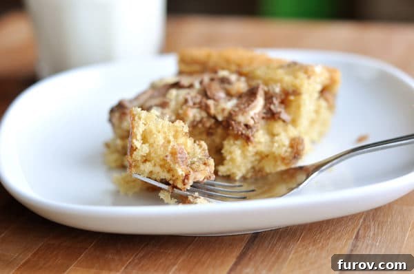 A beautifully presented slice of cake with Heath Bar crushed on top, on a pristine white plate, inviting a taste.