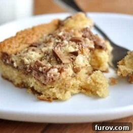 Close-up of a square piece of Heath Bar Cake with melted chocolate and toffee bits on top.