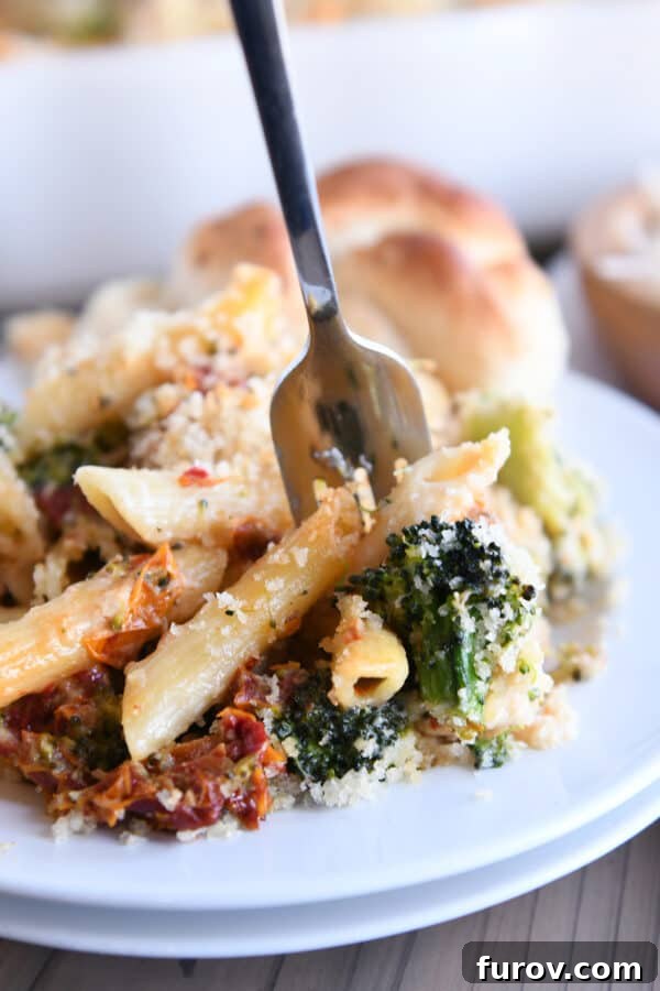 Hearty Chicken and Broccoli Penne Bake with Smoked Mozzarella 8 Close-up of a fork taking a bite of the baked penne casserole, highlighting the savory chicken, tender broccoli, and rich smoked mozzarella.