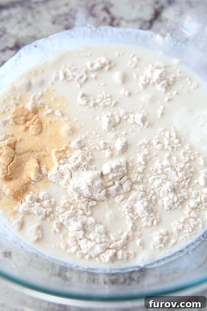 Ultimate Creamy Spinach Artichoke Dip 3 Top down view of a glass bowl with milk, flour, and seasonings, ready for whisking.