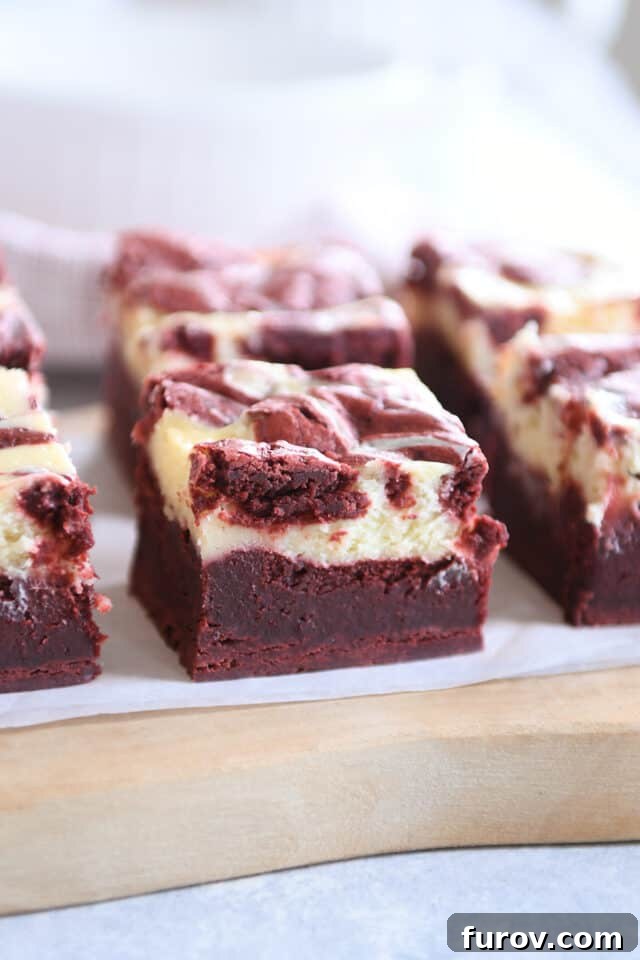Red velvet cheesecake brownie on wood cutting board.