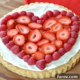 Close-up of a whole fruit pizza with assorted fresh berries and lemon zest.