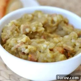 Close-up of a white bowl filled with thick split pea and ham soup with barley.