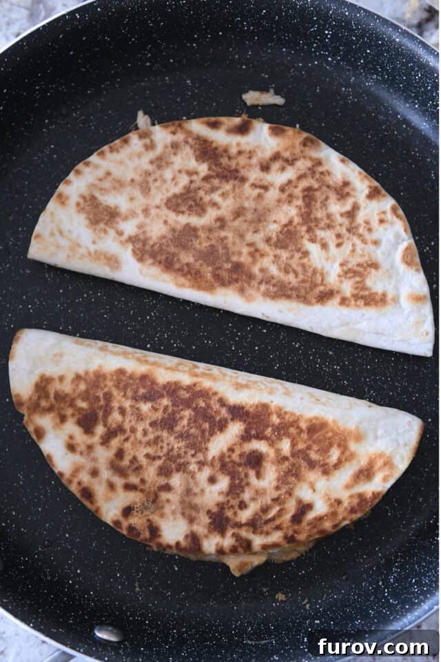 Crispy Chicken Quesadillas: A Culinary Delight 6 Two folded chicken quesadillas sizzling and browning in a hot skillet, showcasing their golden crisp exterior.