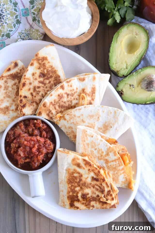 Crispy Chicken Quesadillas: A Culinary Delight 7 A white platter showcasing six beautifully cut chicken quesadilla triangles, accompanied by bowls of vibrant salsa, fresh sliced avocado, and creamy sour cream, ready to be enjoyed.