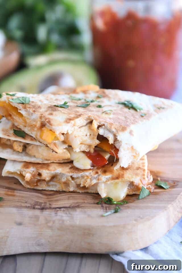 Crispy Chicken Quesadillas: A Culinary Delight 8 Three perfectly cut triangle quesadillas stacked neatly on a rustic wooden board, showcasing their appetizing filling and crispy exterior.