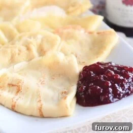 seven folded Swedish pancakes on white tray with jam