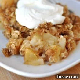 A close-up shot of a baked apple crisp, showcasing its golden-brown, crunchy streusel topping, indicating a perfectly cooked dessert.