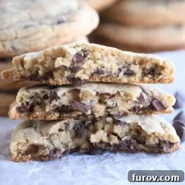 three half chocolate chip cookies stacked on each other on white parchment paper