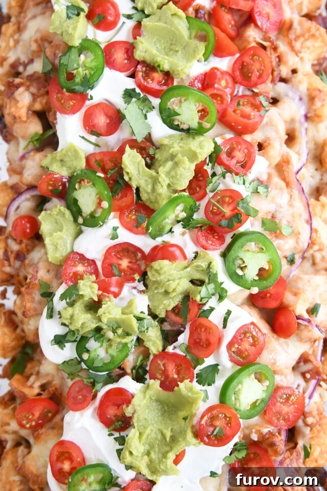 Close up top down view of bbq chicken totchos with sour cream, tomatoes and guacamole.