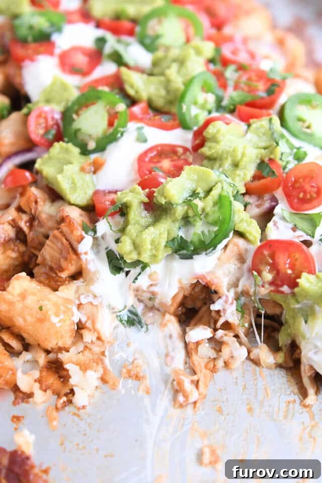 BBQ chicken tater tot nachos on sheet pan with helping taken out.