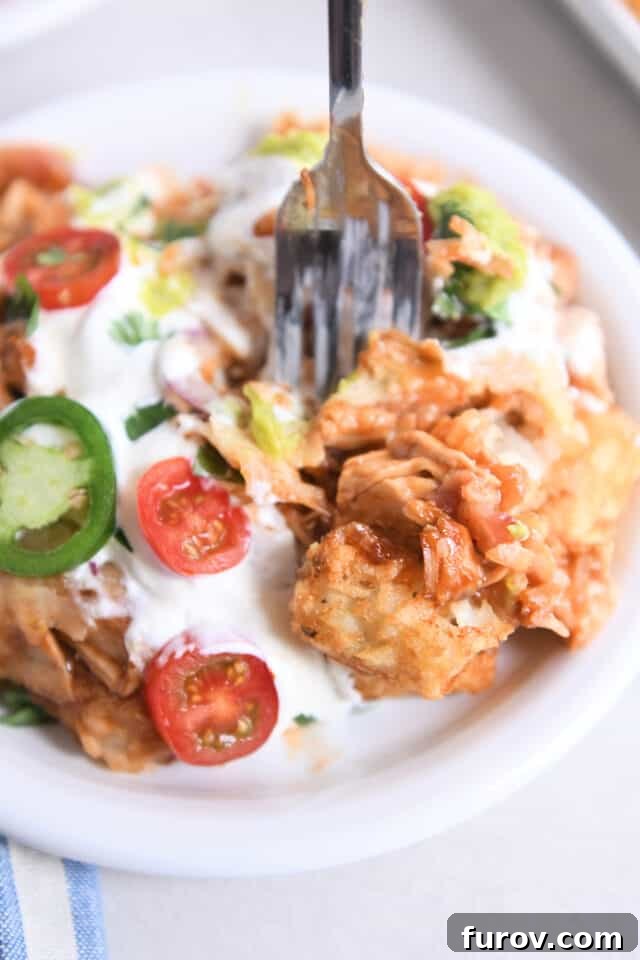 Fork digging into plate of bbq chicken totchos.