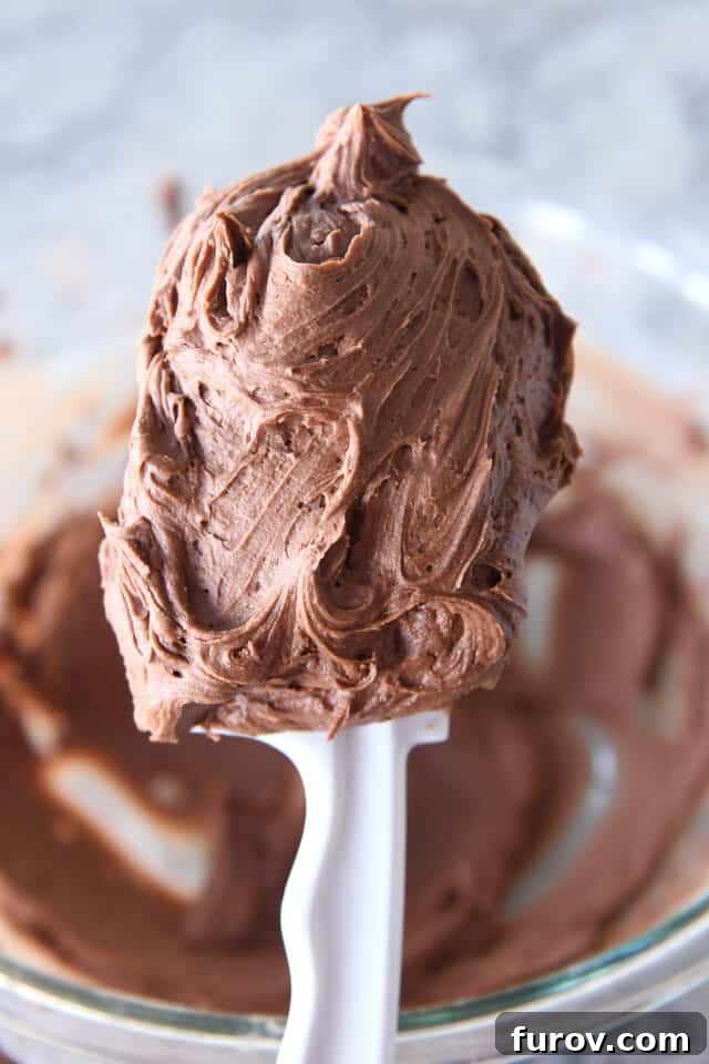 Swirly scoop of chocolate buttercream frosting on white spatula.