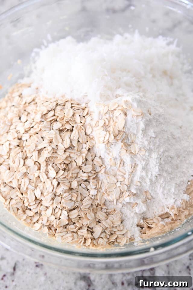 A bowl filled with a base of flour, oats, and coconut, ready for the wet ingredients and mix-ins to create the perfect cowboy cookie dough.
