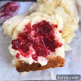 A close-up of a Butter Swim Biscuit, adorned with a swirl of raspberry jam and a dollop of butter, ready to be enjoyed.