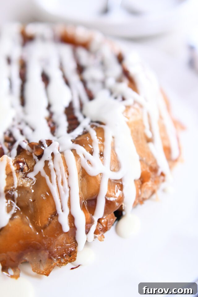 Side view of upside down apple pie with glaze drizzled over the top.