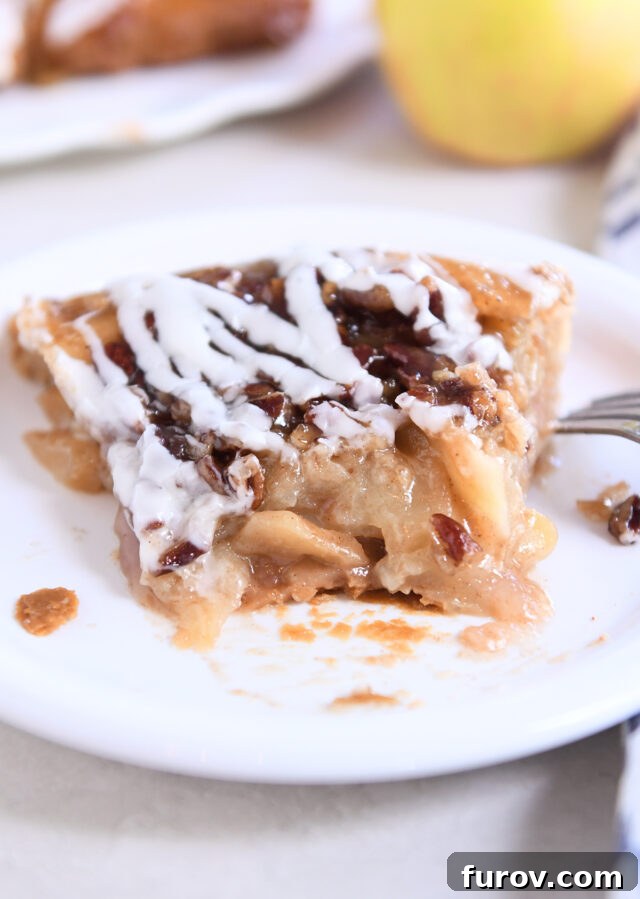 Piece of apple pie on white plate with one bite gone.