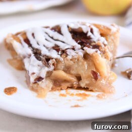 Slice of apple pie on white plate with one piece gone.