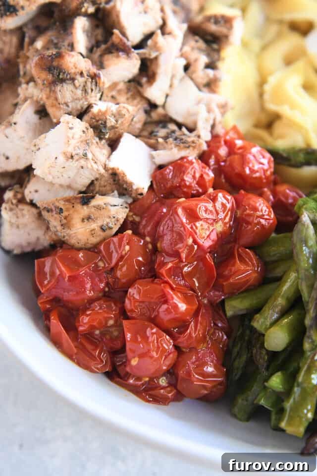 Tangy Pesto Balsamic Chicken Tortellini Medley 5 A white bowl filled with glistening roasted cherry tomatoes, placed next to slices of tender grilled chicken.