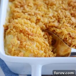 Scooping out a spoonful of cheesy funeral potatoes, revealing the creamy texture and melted cheese.