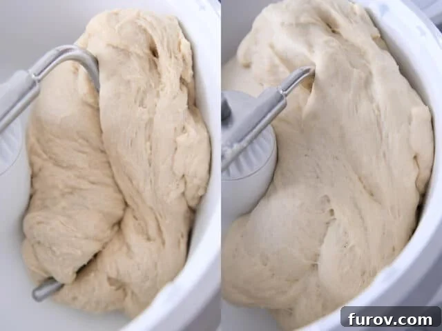 Soft dinner roll dough, perfectly risen and doubled in volume, resting in a white stand mixer bowl with the dough hook, ready for the next step.