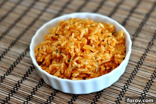 A small white ramekin filled with vibrant, fluffy Mexican rice, garnished with fresh cilantro.