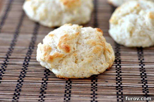 A close-up shot of a stack of golden brown easy flaky buttermilk drop biscuits, ready to be enjoyed.