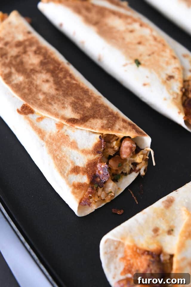 Cheesy Crispy Chicken Enchilada Wraps 6 Multiple tortilla wraps, generously filled with a savory mixture of beans, chicken, and rice, sizzling and transforming into a perfect crisp on a nonstick griddle, showcasing their appetizing golden-brown evolution.