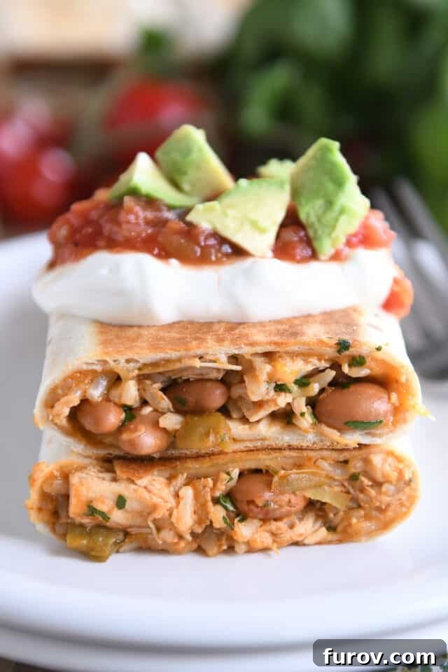 Cheesy Crispy Chicken Enchilada Wraps 8 Two halves of a perfectly crispy chicken enchilada wrap, beautifully arranged and generously topped with fresh sour cream, vibrant salsa, and creamy avocado slices, showcasing an enticing and appetizing serving presentation.