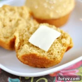 A single whole wheat dinner muffin with sesame seeds on top, showcasing its golden-brown crust.