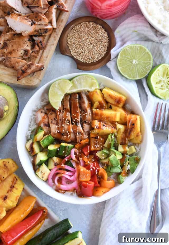 White bowl with grilled chicken, avocados, fresh lime wedges, pineapple, and peppers surrounded by limes, picked onions and other ingredients.