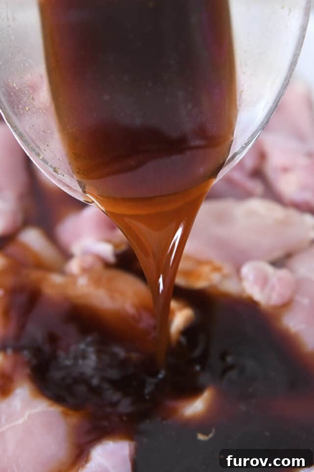 Pouring teriyaki marinade over chicken.