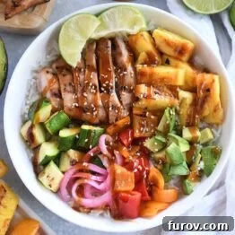 White bowl with grilled chicken, avocados, fresh lime wedges, pineapple, and peppers surrounded by limes, picked onions and other ingredients.