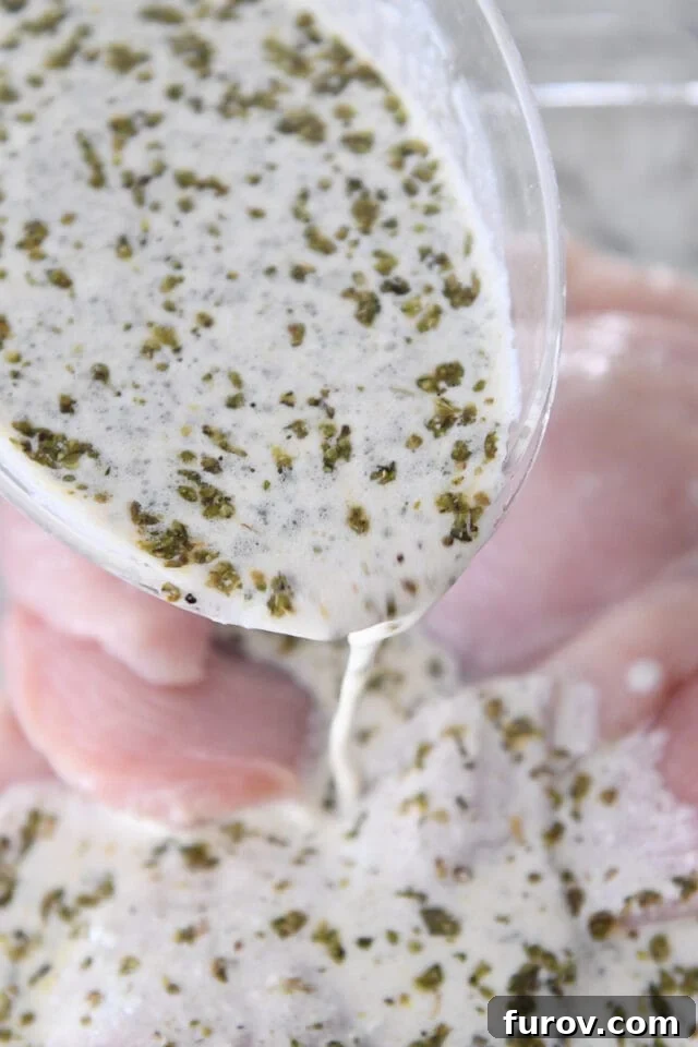 Ultimate Easy Chicken Gyros 3 Pouring zesty yogurt marinade over raw chicken breasts in a bowl.