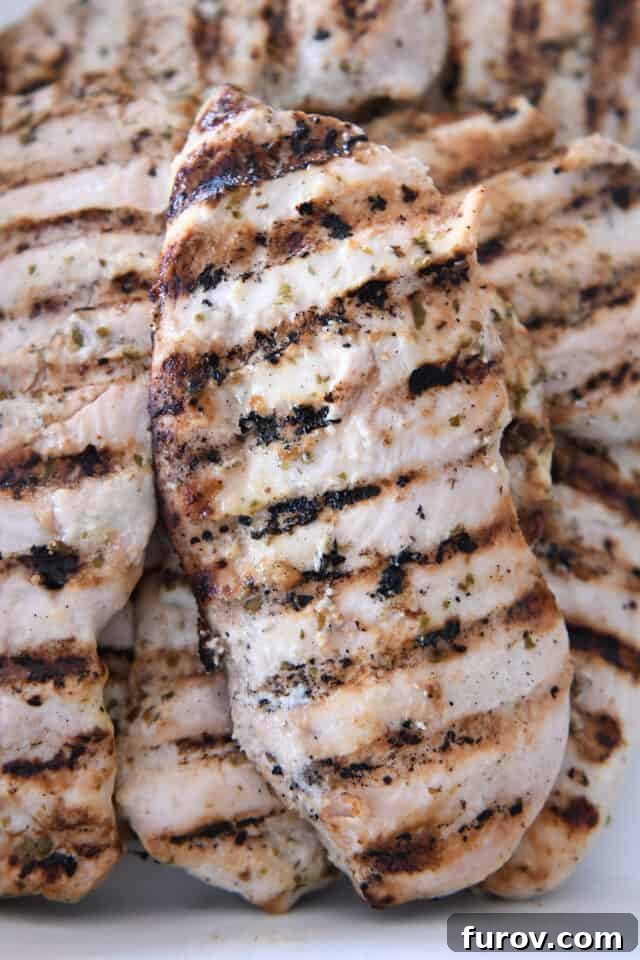 Ultimate Easy Chicken Gyros 4 Perfectly grilled chicken breasts, ready for slicing, arranged in a white serving dish.