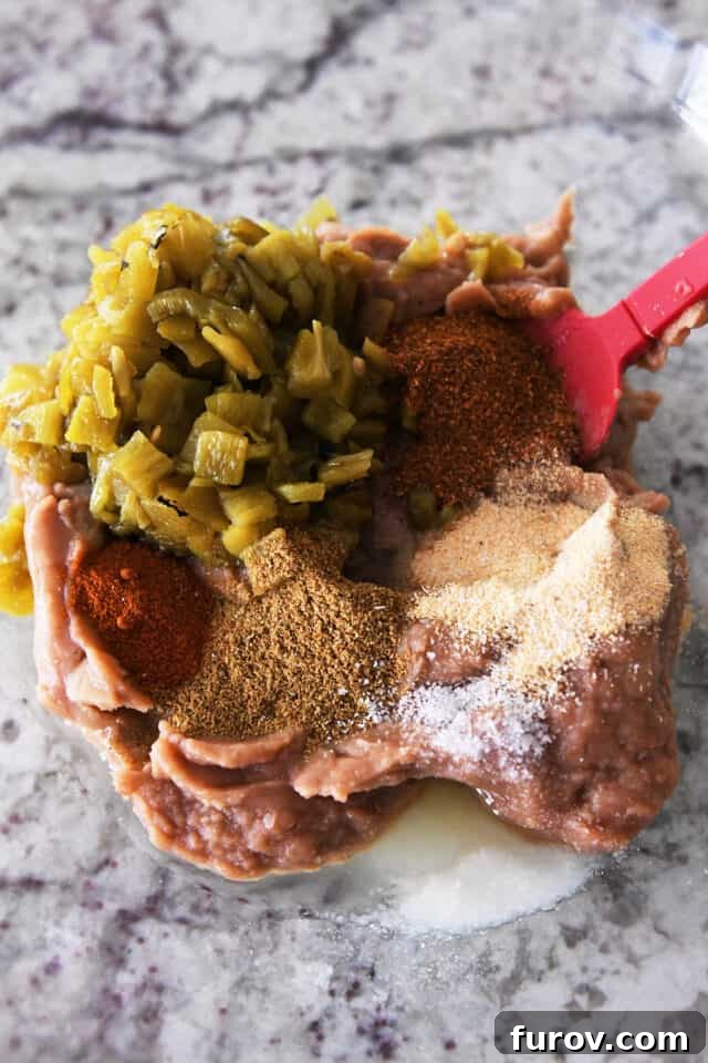 A glass bowl showcasing the perfectly mixed ingredients for the wrap filling, including refried beans, green chiles, chili powder, cumin, paprika, and salt.