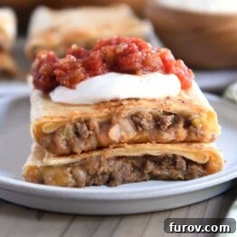 Two half beef and bean wraps on gray plate with salsa and sour cream.